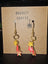 Colorful star-shaped polymer clay earrings with gold hooks hanging on a brown craft display card with 'ONNASTY CRAFTS' and a spider illustration