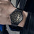 Black men's luxury automatic mechanical watch with a round dial, intricate skeleton design, stainless steel strap, and modern style
