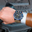 Luxury men's chronograph sports watch with large 48.5mm black bezel, black leather strap, rose gold case, and detailed dial with subdials and date window