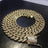 Gold Cuban link necklace with 8mm width, encrusted with sparkling cubic zirconia stones, featuring a secure clasp, on black background