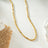 Gold beaded dainty chain necklace with small square beads, resting on a decorative ceramic dish with a scalloped edge, ideal for layering or everyday wear