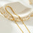 Gold beaded dainty chain necklace with small square beads, resting on a decorative ceramic dish with a scalloped edge, ideal for layering or everyday wear