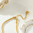 Gold beaded dainty chain necklace with small square beads, resting on a decorative ceramic dish with a scalloped edge, ideal for layering or everyday wear