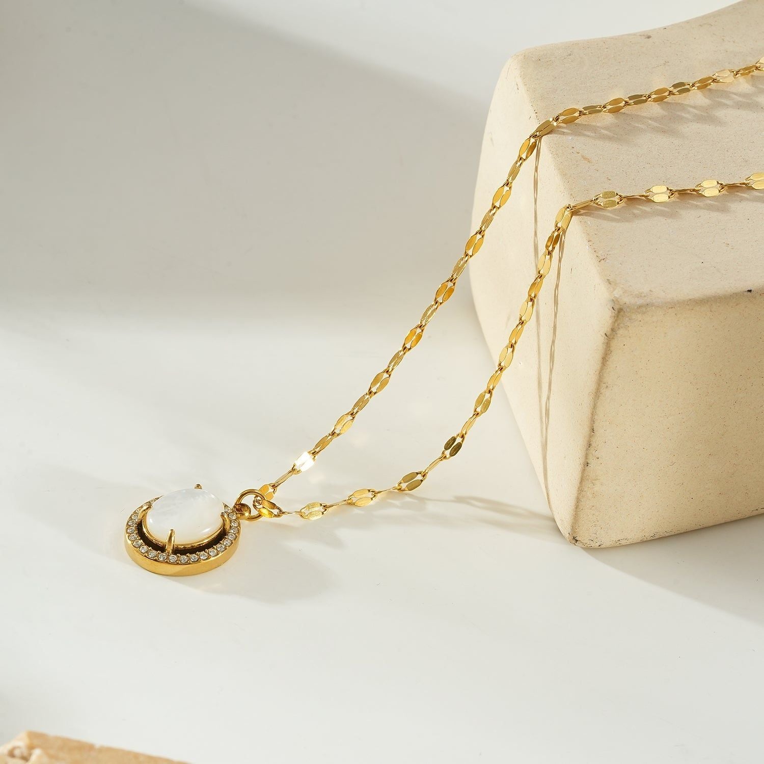 Gold pendant necklace with a freshwater pearl center, surrounded by a halo of sparkling zirconia stones, on a delicate gold chain