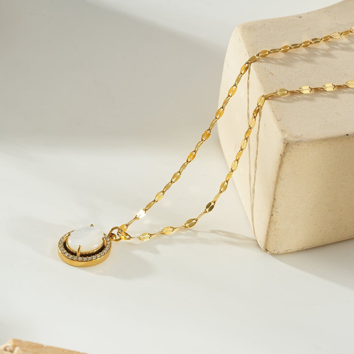 Gold pendant necklace with a freshwater pearl center, surrounded by a halo of sparkling zirconia stones, on a delicate gold chain