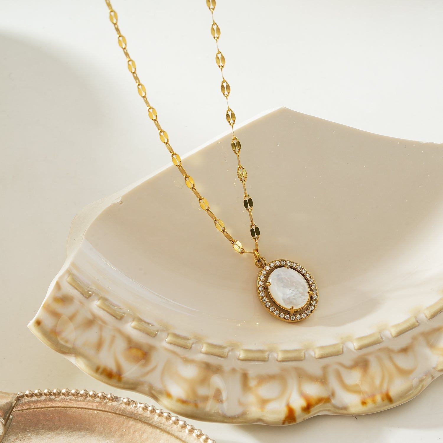 Gold pendant necklace with a freshwater pearl center, surrounded by a halo of sparkling zirconia stones, on a delicate gold chain