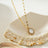 Gold pendant necklace with a freshwater pearl center, surrounded by a halo of sparkling zirconia stones, on a delicate gold chain