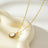 Gold pendant necklace with a freshwater pearl center, surrounded by a halo of sparkling zirconia stones, on a delicate gold chain