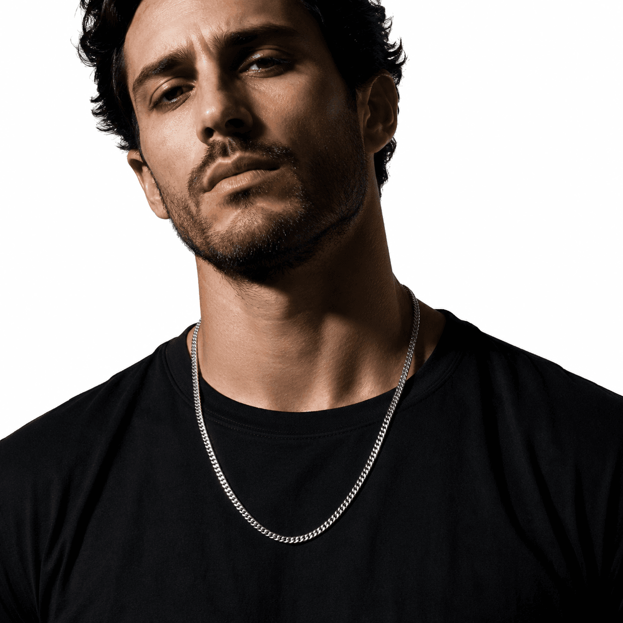 Silver Cuban link chain necklace on a male model with dark hair, wearing a black t-shirt, close-up shot, sleek and stylish jewelry