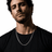 Silver Cuban link chain necklace on a male model with dark hair, wearing a black t-shirt, close-up shot, sleek and stylish jewelry
