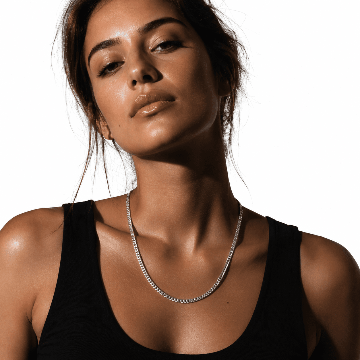 Silver Cuban link chain necklace on a male model with dark hair, wearing a black t-shirt, close-up shot, sleek and stylish jewelry