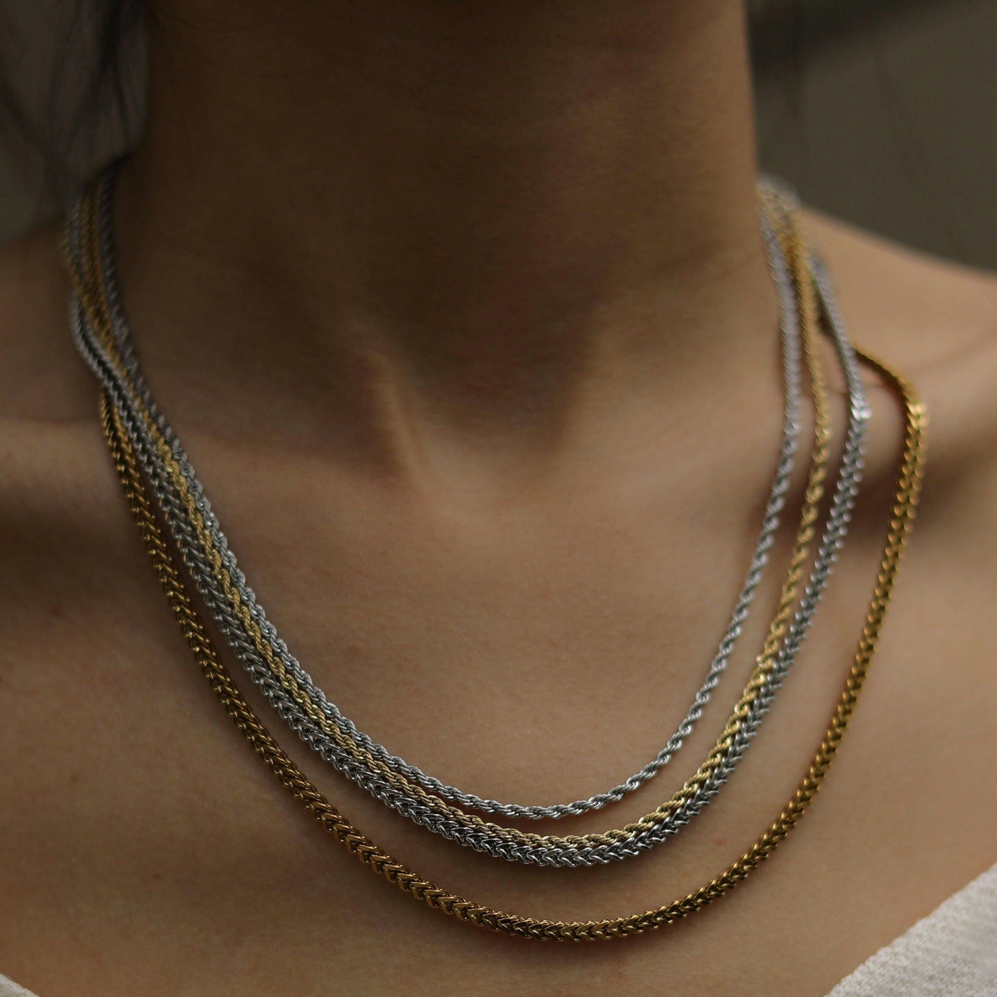 Silver Cuban link chain necklace on a male model with dark hair, wearing a black t-shirt, close-up shot, sleek and stylish jewelry