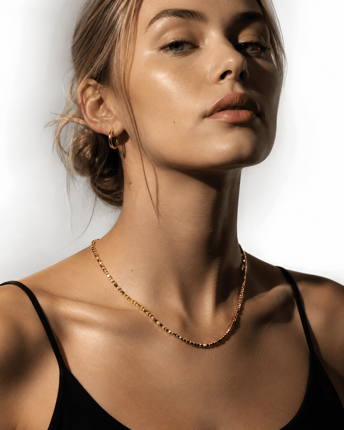 Gold beaded dainty chain necklace with small square beads, resting on a decorative ceramic dish with a scalloped edge, ideal for layering or everyday wear